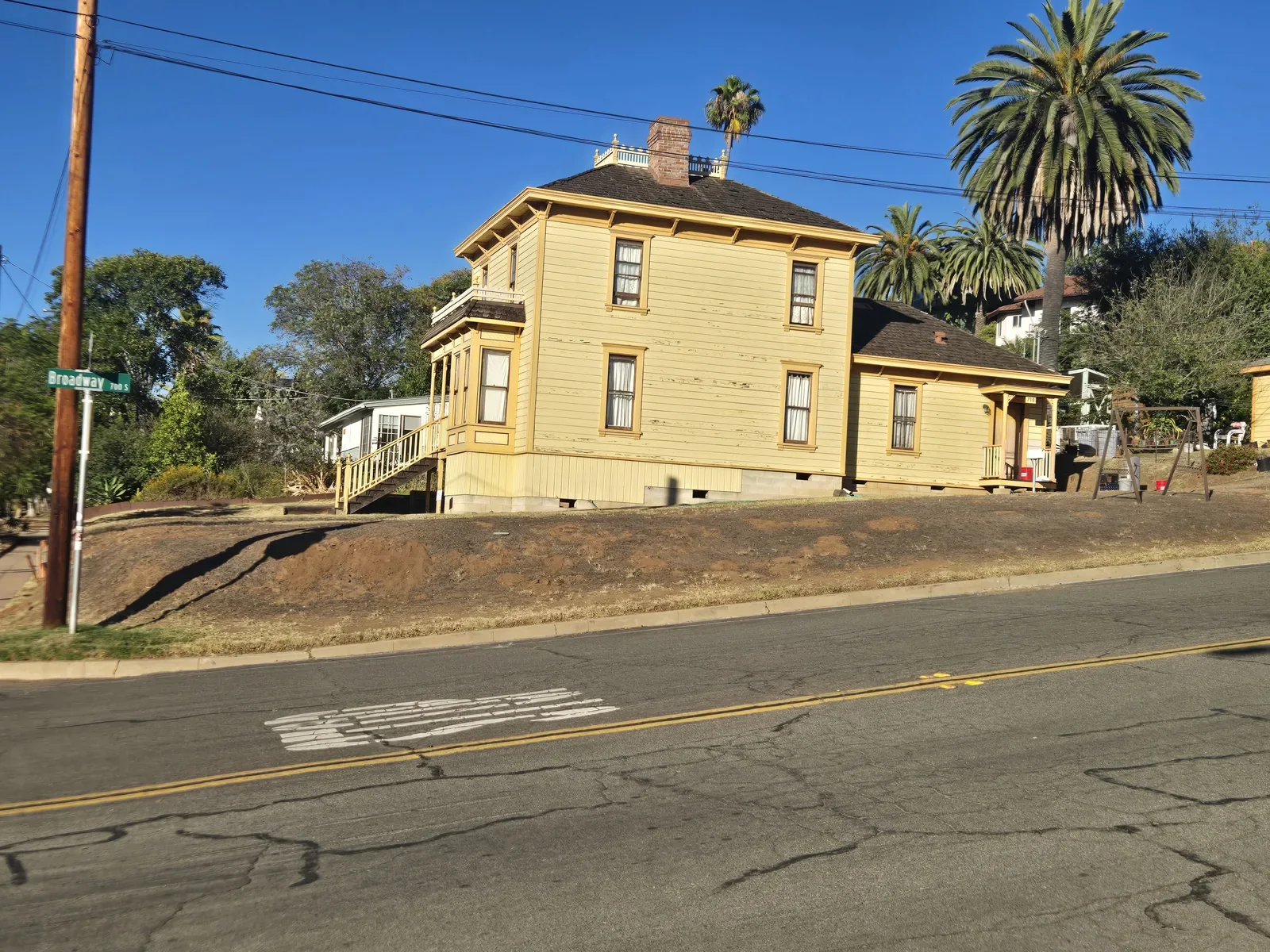 Historic two-story house at 710 South Broadway in Old Escondido with a large Canary Island date palm rising beside the roofline